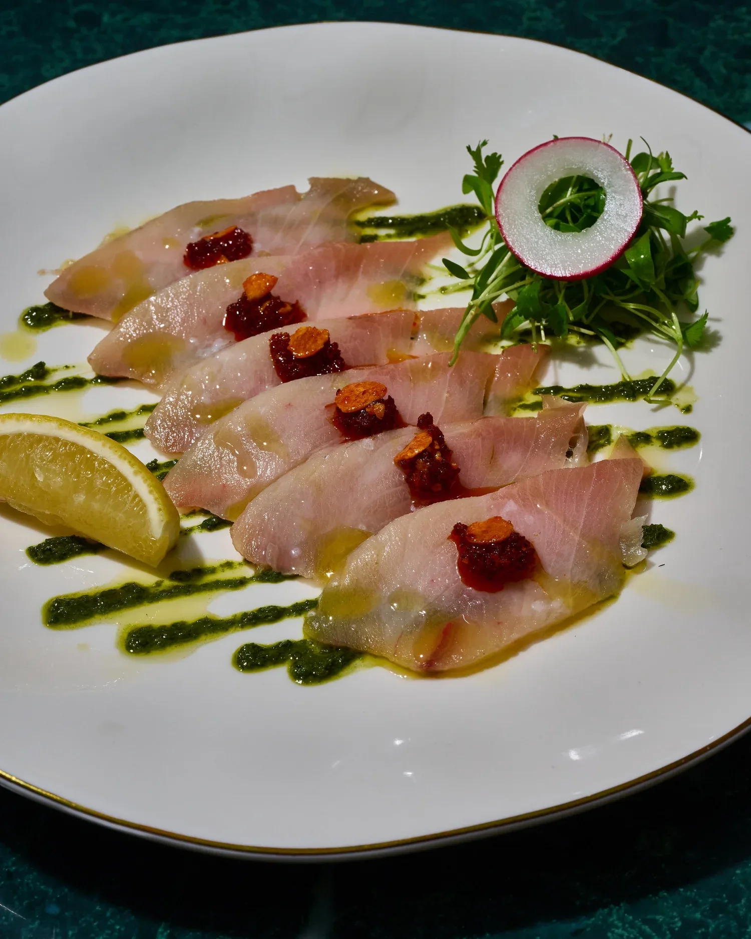 Hamachi crudo arranged with citrus, herbs, and olive oil